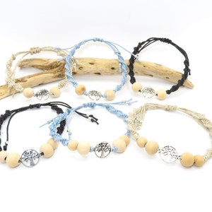 Op de afbeelding: Vijf armbanden met houten kralen en een zilveren levensboombedel. De armbanden zijn gemaakt met verschillende gekleurde koorden: zwart, beige en blauw.