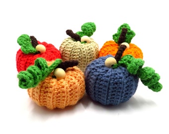 May include: Five crocheted pumpkins in different colors, including orange, red, blue, green, and beige. Each pumpkin has a wooden stem and green crocheted leaves.