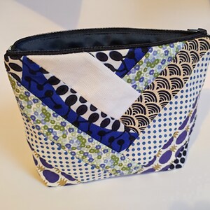 Peut inclure: Une trousse de maquillage matelassée avec une variété de tissus à motifs. Le sac est doté d'une fermeture éclair et est fabriqué avec des tissus bleus, blancs et à motifs. Les motifs comprennent des pois, des motifs floraux et des motifs abstraits.
