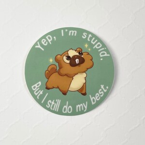 Puede incluir: Una pegatina redonda con un castor de dibujos animados marr&oacute;n y beige, con un diente blanco. El texto dice: "Yep, I'm stupid. But I still do my best." sobre un fondo verde claro.