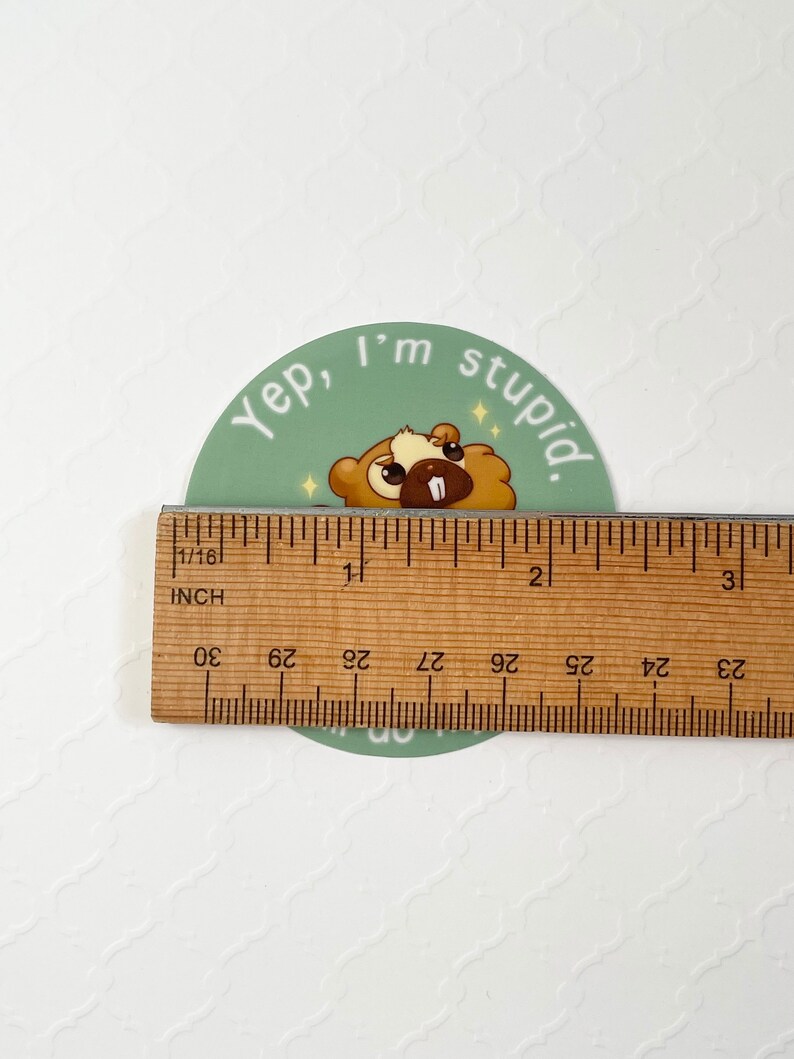 Puede incluir: Una pegatina redonda con un castor de dibujos animados y el texto "Yep, I'm stupid". La pegatina mide aproximadamente 5 cm de di&aacute;metro. El castor es marr&oacute;n y beige con un diente blanco y acentos brillantes.