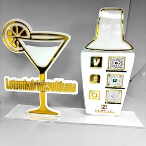 May include: Gold-colored acrylic cutout of a martini glass with a lemon slice and the text "Let's mix drinks with Thana".  A gold-colored acrylic cutout of a cocktail shaker with QR codes and social media icons.  The text "@ExpressiveDesigns" is also included.