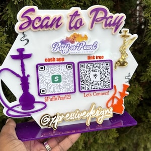 May include: A white hexagonal sign with the text "Scan to Pay" in purple and orange lettering. The sign features a logo for "Puffin Pearl Hookah Company" and two QR codes for "cash app" and "link tree". The sign also includes the text "Let's Connect!" and "@xpressivedesigns".