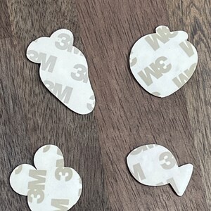 May include: Four white adhesive stickers with a 3M logo. The stickers are shaped like a paw print, a fish, a carrot, and an apple.