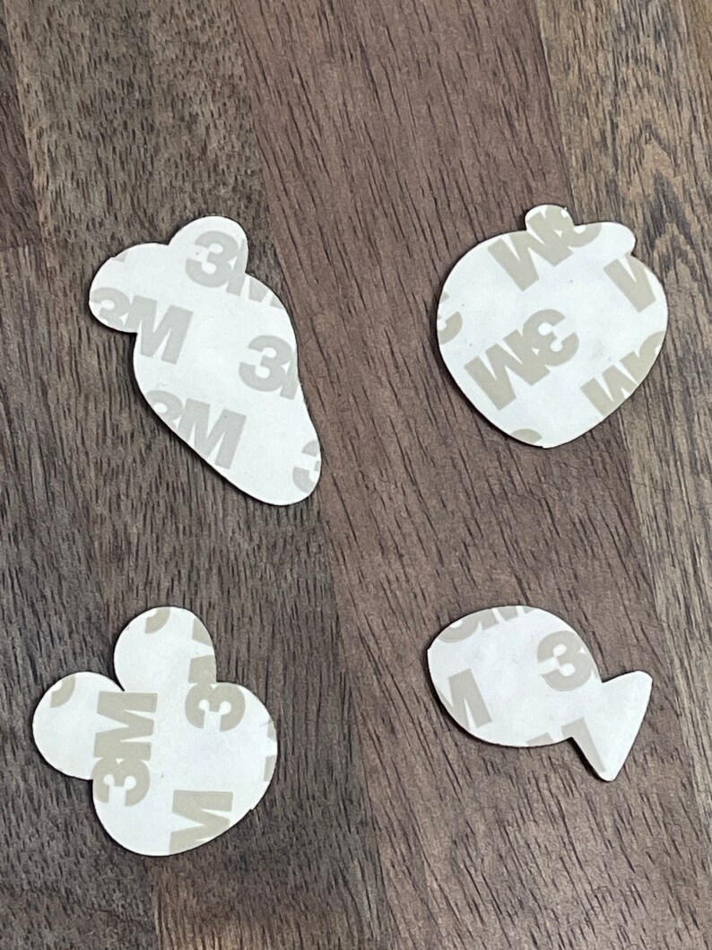 May include: Four white adhesive stickers with a 3M logo. The stickers are shaped like a paw print, a fish, a carrot, and an apple.