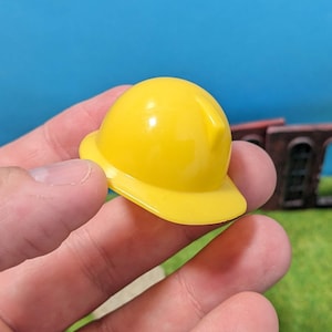 Könnte beinhalten: Ein gelber Plastik-Bauarbeiterhelm.