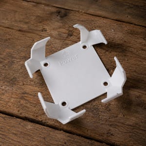 May include: A white square plastic mounting bracket featuring four corner clips and four circular screw holes. The centre of the bracket is embossed with an upward-pointing arrow and the word Power, indicating the correct orientation for installation.