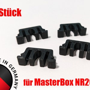Könnte beinhalten: Vier schwarze Kunststoff-Kabelmanagement-Clips zur Verwendung in einem Computergehäuse. Die Clips sind so konzipiert, dass sie Kabel an Ort und Stelle halten und organisieren. Der Text "4 stück" und "für MasterBox NR200" ist im Bild sichtbar.