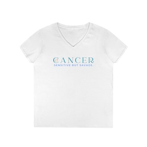 May include: White V-neck t-shirt with the word "CANCER" in teal, with a crab symbol above the word "CANCER". Below the word "CANCER" is the phrase "SENSITIVE BUT SAVAGE."