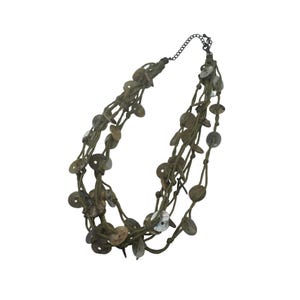 May include: A multi-strand necklace featuring olive green cord and circular, flat, natural-toned beads. The necklace has a dark metal chain and clasp. The beads vary in color from light tan to darker brown.