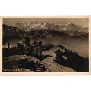 May include: Sepia-toned vintage postcard featuring a large building atop a mountain ridge, with a backdrop of snow-capped mountains. The text "Rigi-Kulm und die Berneralpen" is visible at the bottom. The postcard evokes a sense of history and travel.