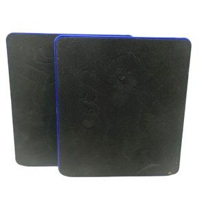 Op de afbeelding: Twee zwarte schuimmatrijzen met blauwe randen. De matrijs rechts heeft een ontwerp van een beer die een kleinere beer met een hart vasthoudt.