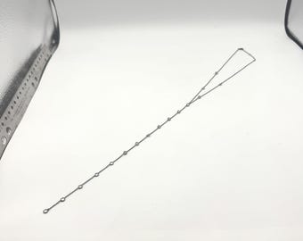 Könnte beinhalten: Eine zarte silberne Halskette mit einer Reihe kleiner, runder, klarer Edelsteine, die gleichmäßig verteilt sind. Die Halskette hat ein schlichtes, elegantes Design, das für den Alltag oder besondere Anlässe geeignet ist. Die Edelsteine sind in einer Silberkette gefasst.
