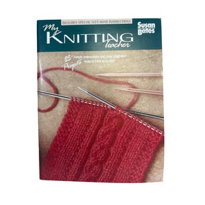 May include: A book titled "My Knitting Teacher" by Susan Bates. The cover is green and tan with the title in white and the image shows red knitting with needles. The book includes instructions for left-handed knitters and 25 projects.