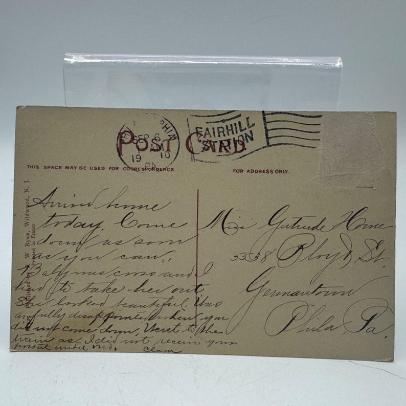 K&ouml;nnte beinhalten: Vintage Postkarte mit handschriftlichem Text und Poststempeln. Die Postkarte hat einen Poststempel aus Philadelphia, PA, vom 10. Oktober 1919, und ist an Miss Gertrude Home adressiert. Die Karte ist beige mit schwarzer Tinte.