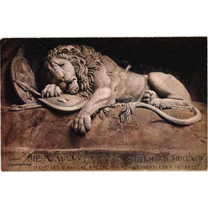 May include: A detailed stone carving of a sleeping lion, resting on a shield and spear. The sculpture is in a sepia tone, with visible text at the bottom. The lion's mane is intricately detailed, and the overall scene evokes a sense of history and remembrance.