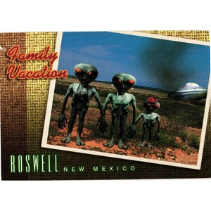 May include: A postcard depicting a family of green aliens in Roswell, New Mexico. The aliens are in a field with a UFO in the background. The postcard reads "Family Vacation" and "Roswell New Mexico".