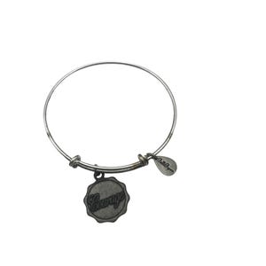 May include: A silver-toned bangle bracelet with a round, adjustable design. A circular charm with the word "Courage" is suspended from the bracelet. A small, teardrop-shaped tag with text is also attached.