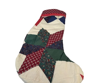 Puede incluir: Una media de Navidad acolchada con un patrón de estrella en rojo, verde, azul y blanco.