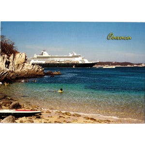 May include: A scenic postcard featuring a large cruise ship sailing on turquoise waters near a rocky coastline. The postcard has the word "Oaxaca" in a yellow cursive font. Several people are swimming in the clear water near the shore.