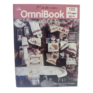 May include: The OmniBook for Bed & Bath, 3rd in the series, features 103 designs by Jeanette Crews Designs. The cover displays various cross-stitch projects including towels, framed art, and decorative items arranged around a bathtub filled with bubbles.