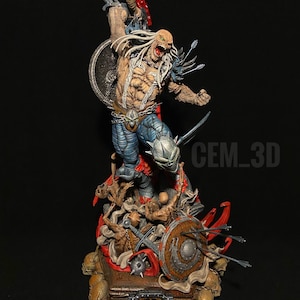 May include: A detailed figurine of a muscular, pale-skinned warrior with long white hair, blue pants, and armor. The figure is holding a shield and a weapon, with arrows piercing its back. The base features skulls, swords, and a shield, with the text "CEM_3D".