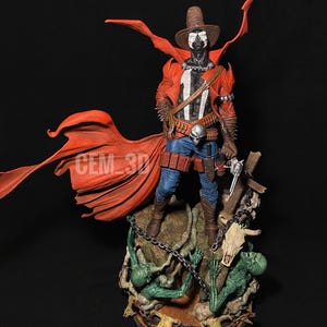 Könnte beinhalten: Detaillierte Figur einer Figur in einem roten Mantel und Cowboyhut, mit einer Schnalle in Schädelform und einer Pistole. Die Figur steht auf einer Basis mit grünen Kreaturen und einem Schädel.