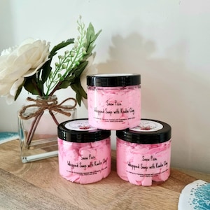 May include: Three pink jars of whipped soap with kaolin clay. The jars have black lids and are labelled "Snow Pixie Whipped Soap with Kaolin Clay".