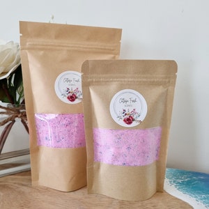 May include: Two brown paper bags containing pink bath salts. The bags feature a white label with the text "Cottage Fresh Scents" and a floral design.