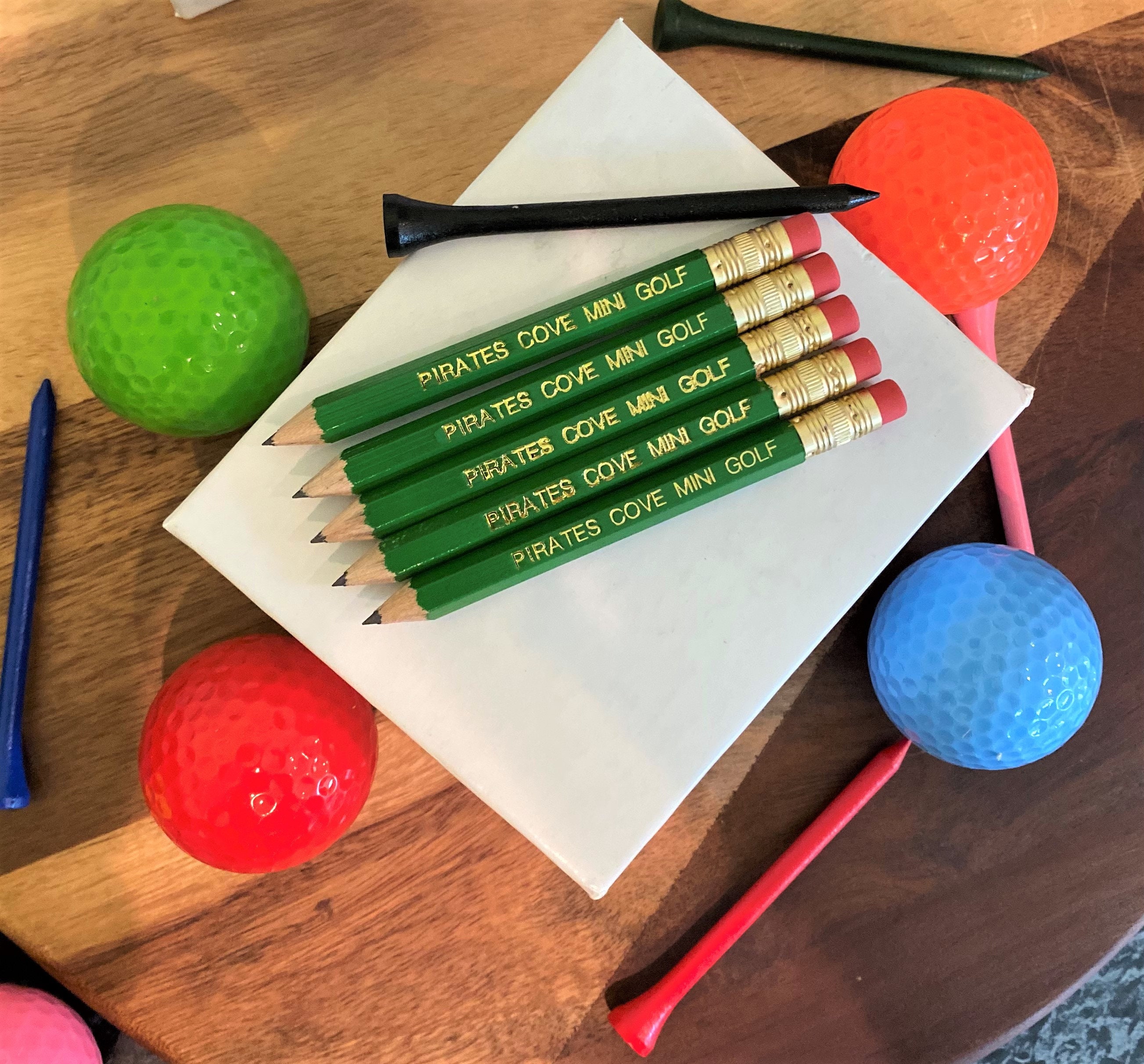 small pencils surrounded by multi-color golf balls and tees