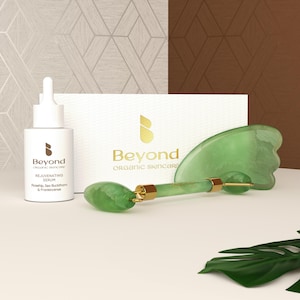 May include: A green jade facial roller and gua sha set with a gold handle. The set is packaged in a white box with the Beyond Organic Skincare logo. The serum bottle is labeled "Beyond Organic Skincare Rejuvenating Serum Rosehip, Sea Buckthorn & Frankincense"