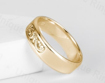 May include: A gold wedding band with a decorative, intricate design on the side.