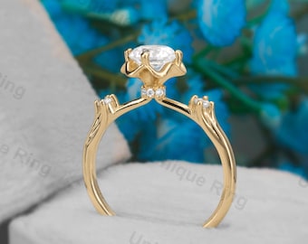 May include: A gold engagement ring with a large, round, clear center stone and smaller stones on the band. The ring is in a blue velvet ring box.