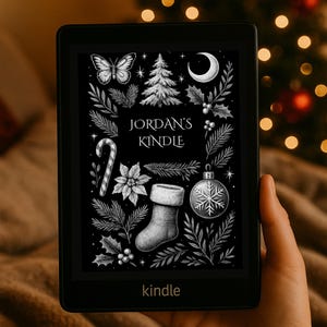 Puede incluir: Un lector de libros electrónicos Kindle negro que muestra una ilustración navideña en escala de grises. El diseño incluye una mariposa, un árbol de Navidad, una luna, acebo, un bastón de caramelo, una flor de pascua, un calcetín y un adorno de copo de nieve. El texto "JORDAN'S KINDLE" está centrado. La palabra "kindle" está en la parte inferior.