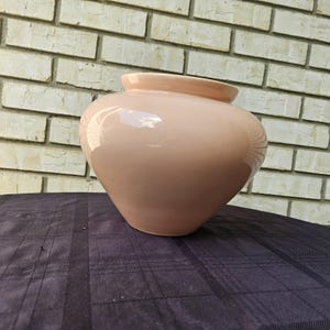 以下が含まれることがあります： 丸みを帯びたバルブ状の薄いピンクのセラミック花瓶。花瓶は滑らかで光沢のある仕上げです。