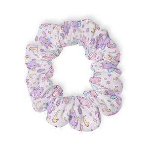 Puede incluir: Coletero blanco con un estampado repetido de unicornios morados, estrellas, arcoíris y lunas crecientes. El coletero está hecho de una tela suave y está diseñado para sujetar el cabello. El diseño presenta colores pastel.