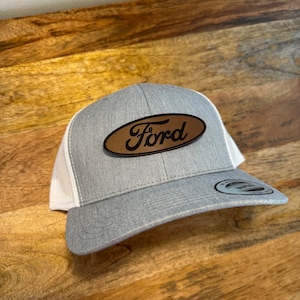 May include: A grey and white baseball cap with a brown leather patch that says "Ford" in a white script font.