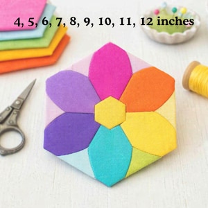 May include: A hexagonal fabric quilt block featuring a central yellow hexagon surrounded by six petal-shaped pieces in pink, orange, yellow, lime green, turquoise, and purple. The text 4, 5, 6, 7, 8, 9, 10, 11, 12 inches is printed above.