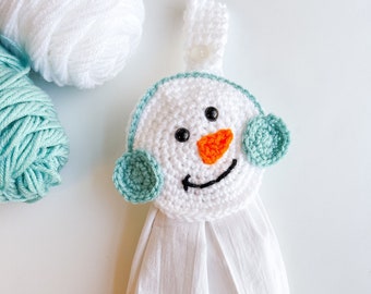 May include: White crocheted snowman towel holder with a green crocheted hat and orange nose.