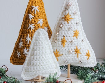May include: Three crocheted Christmas trees, one white and two yellow, decorated with white stars and pearl beads.