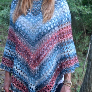 May include: A blue, pink, and white crocheted poncho with a sparkly finish. The poncho has a triangular shape and a scalloped edge.