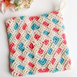 May include: A crocheted pot holder with a diamond pattern in pink, blue, and white.