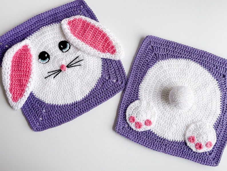 May include: Two crocheted bunny squares, one with a face and ears, the other with a tail and feet. Both squares are purple with white and pink details.