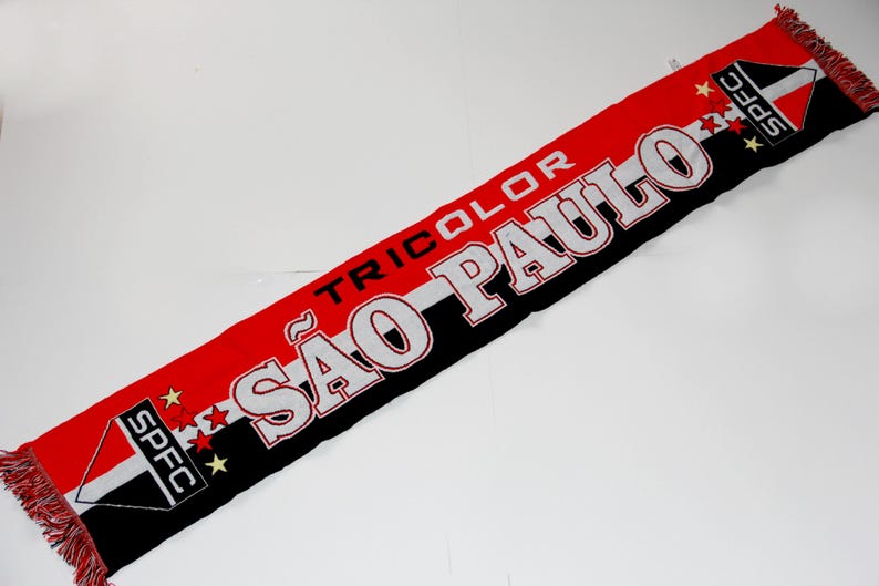 Pu&ograve; includere: Una sciarpa tricolore rossa, nera e bianca del S&atilde;o Paulo FC. La sciarpa presenta il nome della squadra in grandi lettere bianche con contorno nero e la parola "TRICOLOR" sopra. Le estremit&agrave; hanno il logo della squadra e frange.