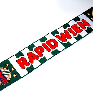 May include: Green and white striped scarf with the words "RAPID WIEN" in red letters. The scarf has a small logo with the word "RAPID" in gold letters and a white and green crest.