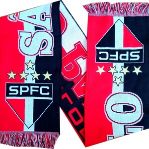 Pu&ograve; includere: Sciarpa rossa, nera e bianca con le lettere "SAO" e "SPFC" visualizzate. La sciarpa ha una frangia alle estremit&agrave; e presenta tre stelle dorate. La sciarpa &egrave; probabilmente un accessorio per una squadra sportiva.