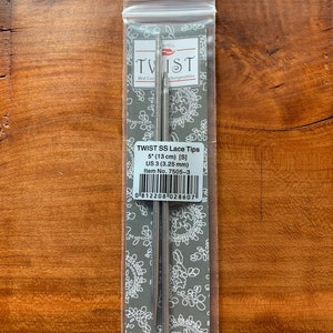 May include: A package of TWIST SS Lace Tips. The package contains two silver knitting needles. The packaging has the text "TWIST" and "Red Lace Interchangeables". The package also has the text "5" (13 cm) [S] US 3 (3.25 mm)".