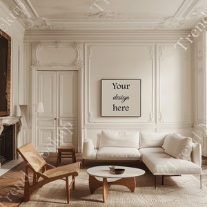 May include: A stylish living room featuring a white corner sofa, a round coffee table, and a wooden chair. A framed print on the wall reads "Your design here". The room has a neutral colour palette with ornate wall panelling and a rug.