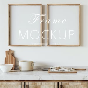 May include: Two wooden picture frames with white mats, hanging on a white wall above a kitchen counter. The frames are empty and ready for your artwork or photos.  The text "Frame Mockup" and "Photoshop File" is printed below the frames.