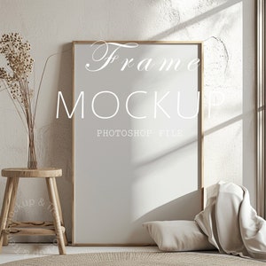 May include: A mockup of a light wood frame with a white background. The frame is sitting on a light brown rug in a room with a white wall and a window. The text "Frame Mockup Photoshop File" is written on the frame.